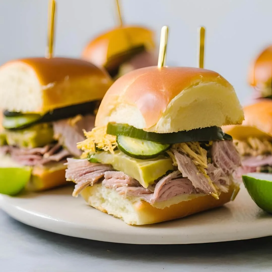 A tray of Cool Cuban Sandwich Sliders, featuring mini cubano rolls filled with thinly sliced roast pork, ham, Swiss cheese, and pickles, pressed and toasted to perfection.