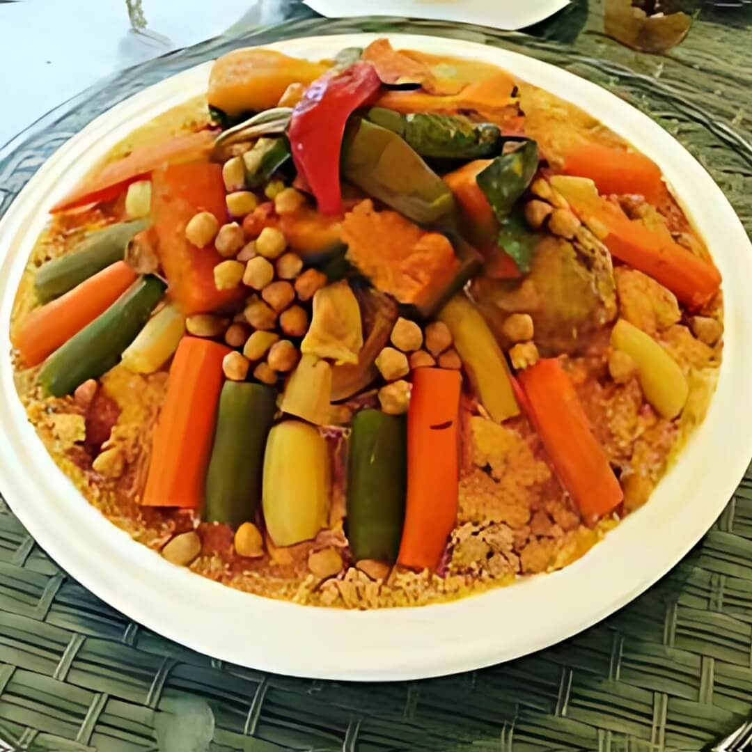 A hearty bowl of Vegetarian Couscous with Seven Vegetables, featuring fluffy couscous mixed with an array of colorful veggies like carrots, zucchini, bell peppers, chickpeas, and spinach, all simmered in a warm spiced broth.